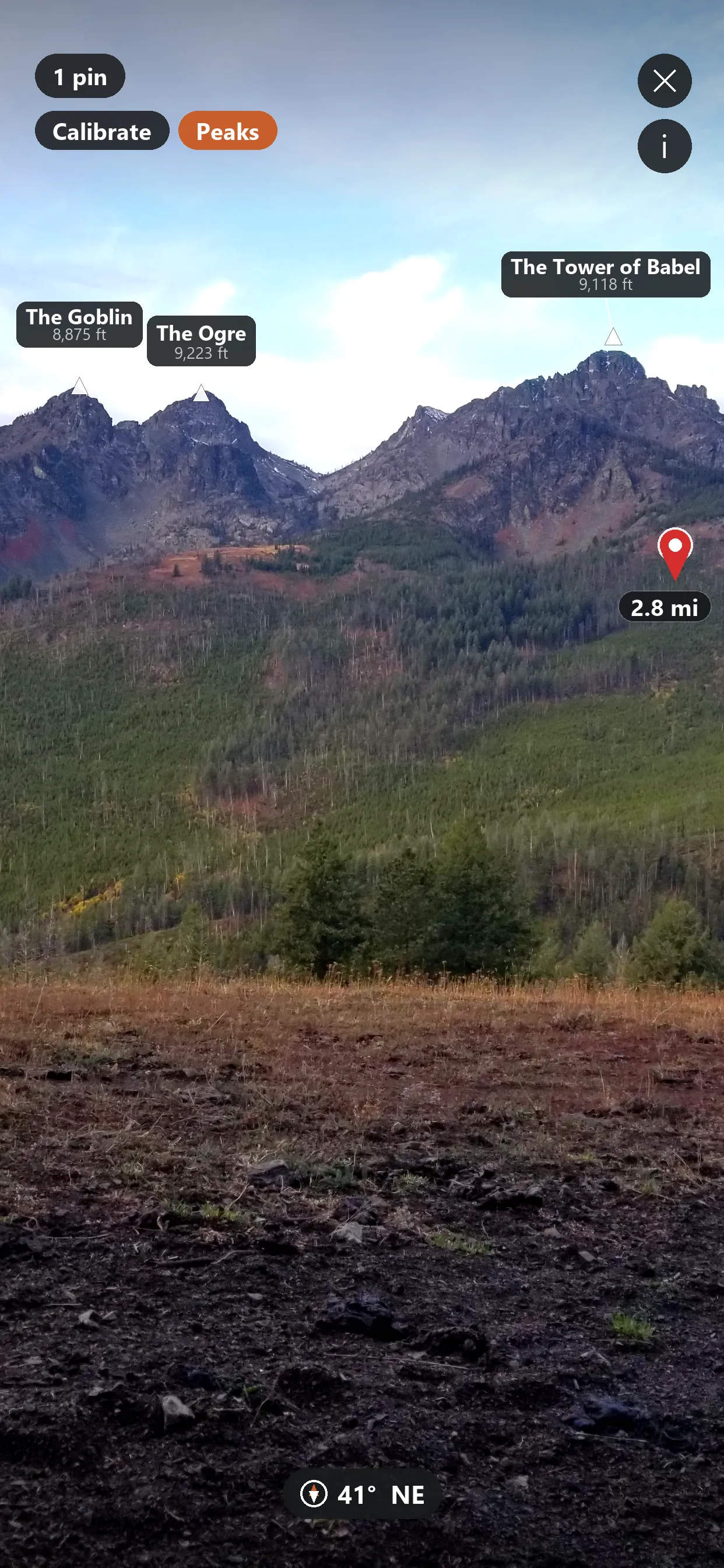 Talus AR mode labeling named peaks and a distance pin over a live camera view of a mountain range.